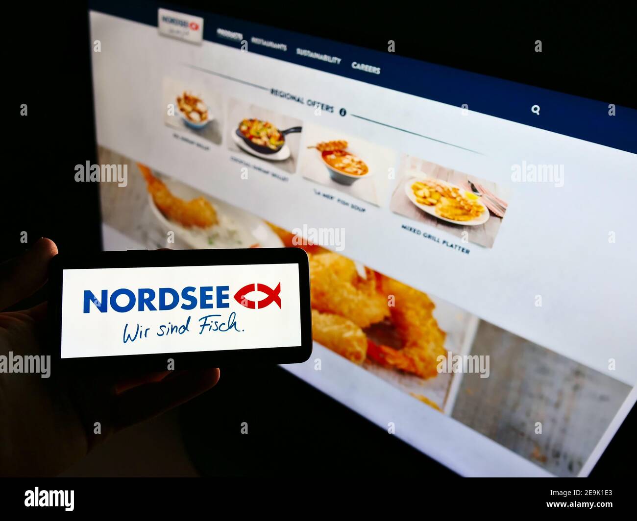 Persona che tiene il cellulare con il logo della catena tedesca di fast-food Nordsee GmbH (frutti di mare) in esposizione davanti al sito web. Mettere a fuoco lo schermo del telefono. Foto Stock