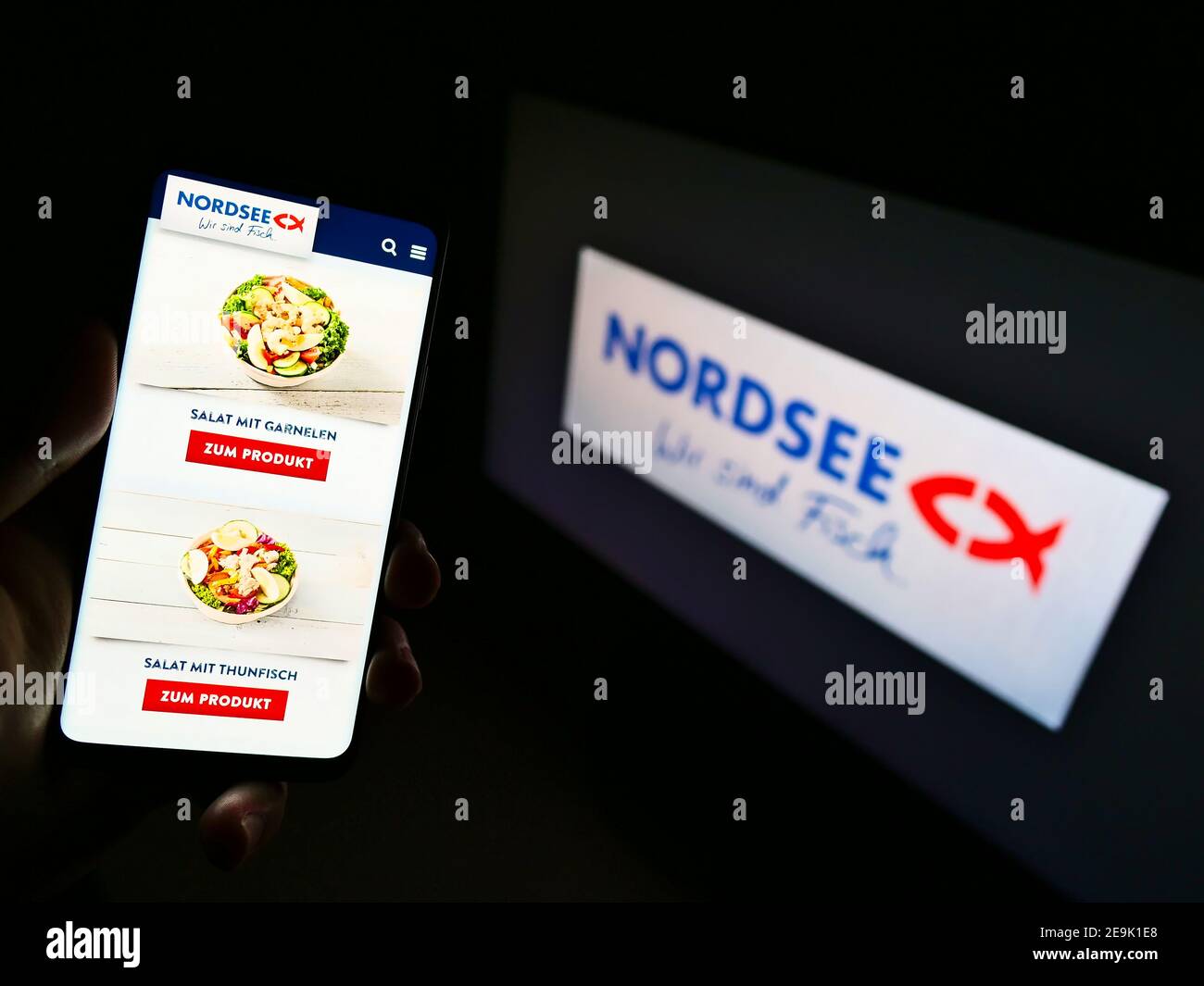 Persona titolare smartphone con prodotti della catena tedesca di ristoranti fast-food Nordsee GmbH in esposizione davanti al logo aziendale. Mettere a fuoco lo schermo del telefono. Foto Stock