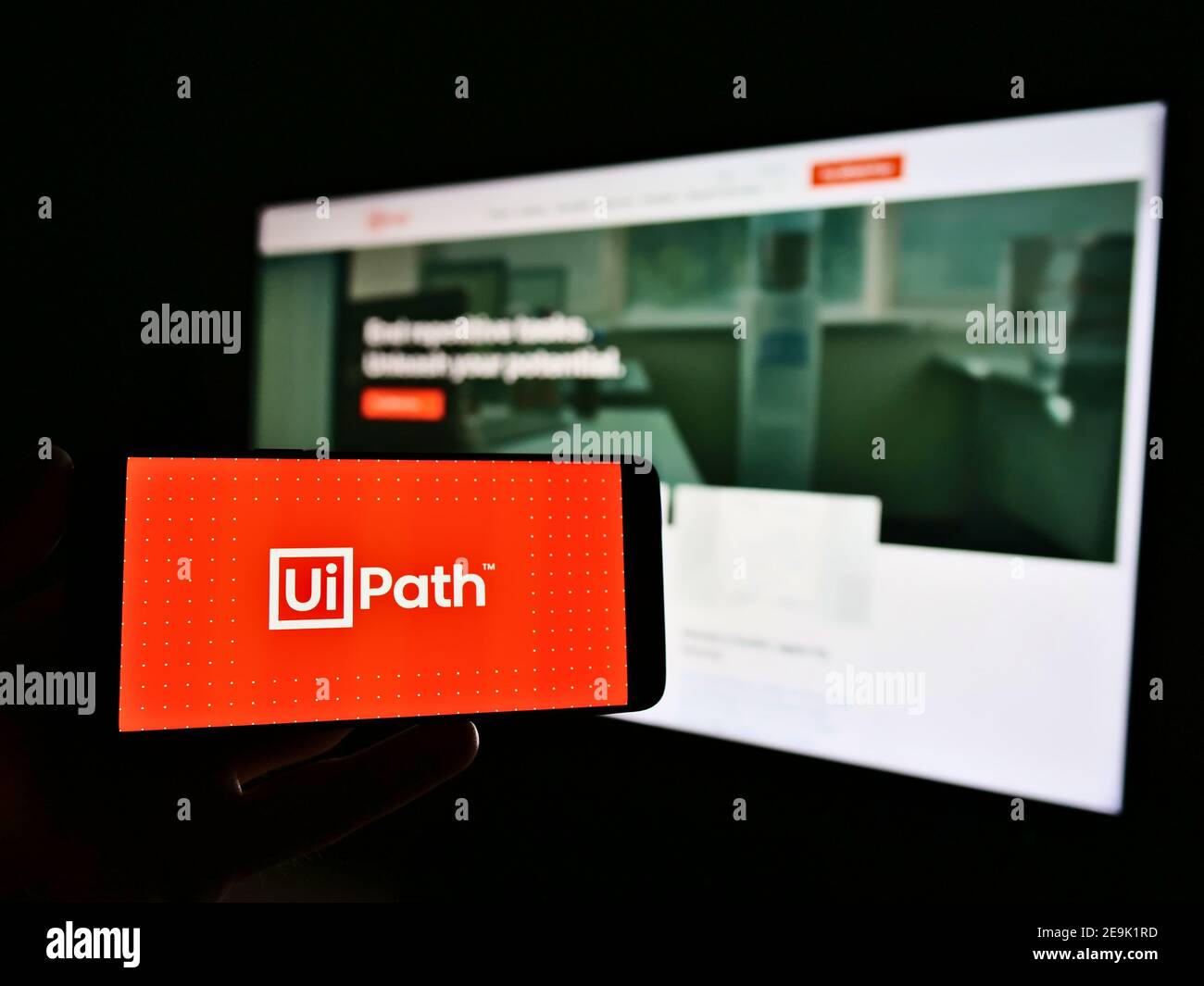 Persona che tiene il cellulare con il logo della società di sviluppo software UiPath Inc. In esposizione davanti alla home page aziendale. Mettere a fuoco lo schermo del telefono. Foto Stock