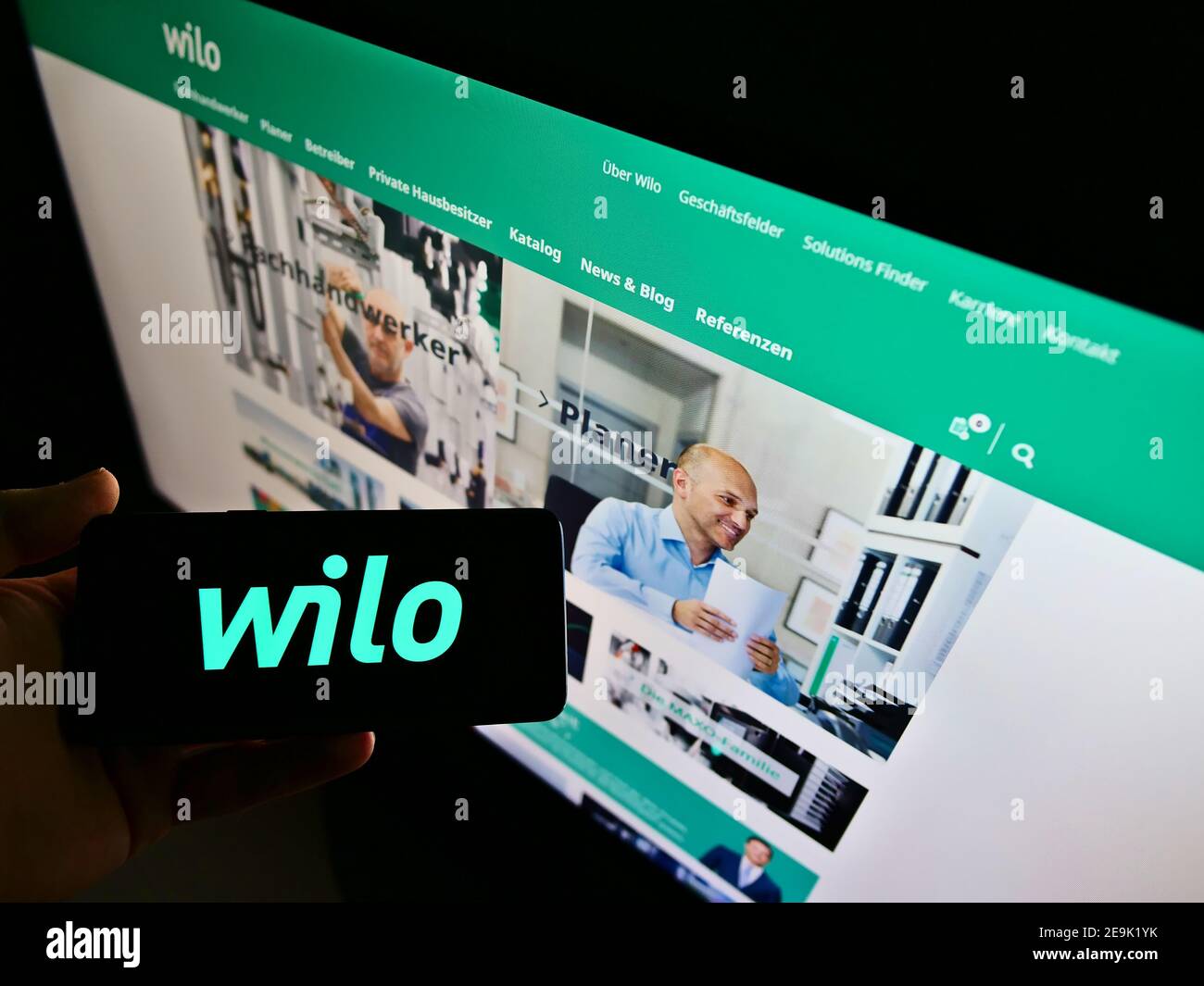 Persona che tiene il telefono cellulare con il logo del produttore tedesco di pompe Wilo se in esposizione davanti al sito web aziendale. Mettere a fuoco sullo schermo del cellulare. Foto Stock