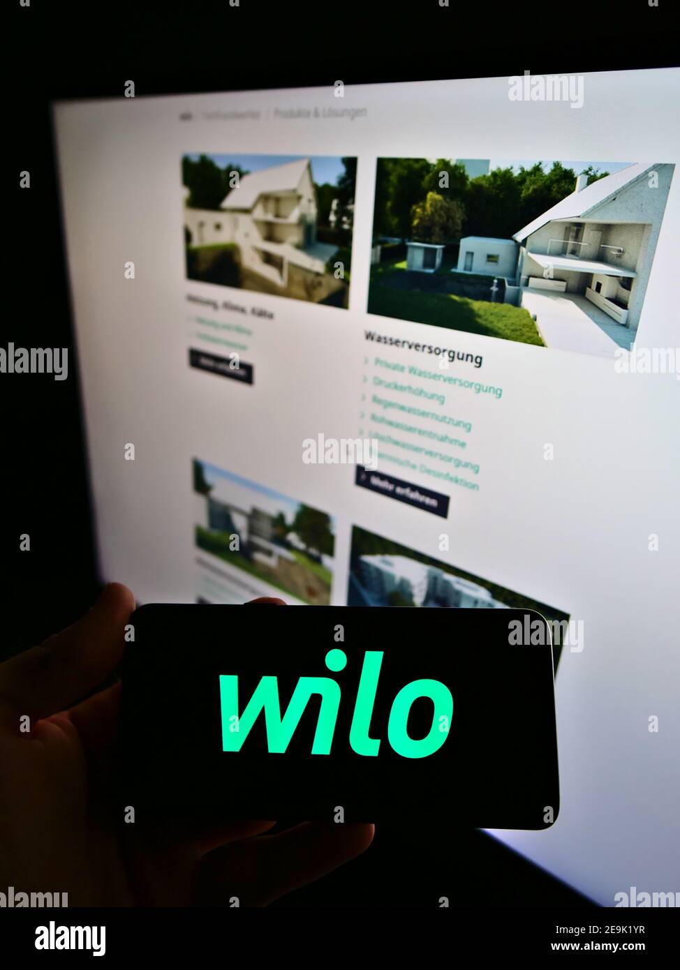 Persona che tiene lo smartphone con il logo del produttore tedesco di pompe Wilo se in esposizione davanti alla pagina web aziendale. Mettere a fuoco lo schermo del telefono. Foto Stock