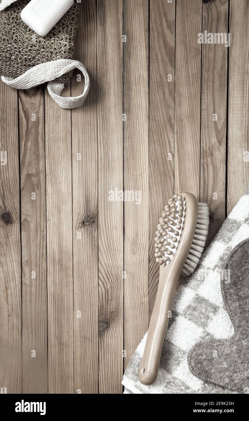 Accessori per la visita di un bagno o sauna su fondo di legno: Asciugamano, panno, spazzola per massaggi, sapone, guanto. Vista dall'alto con spazio per la copia. Disposizione piatta Foto Stock
