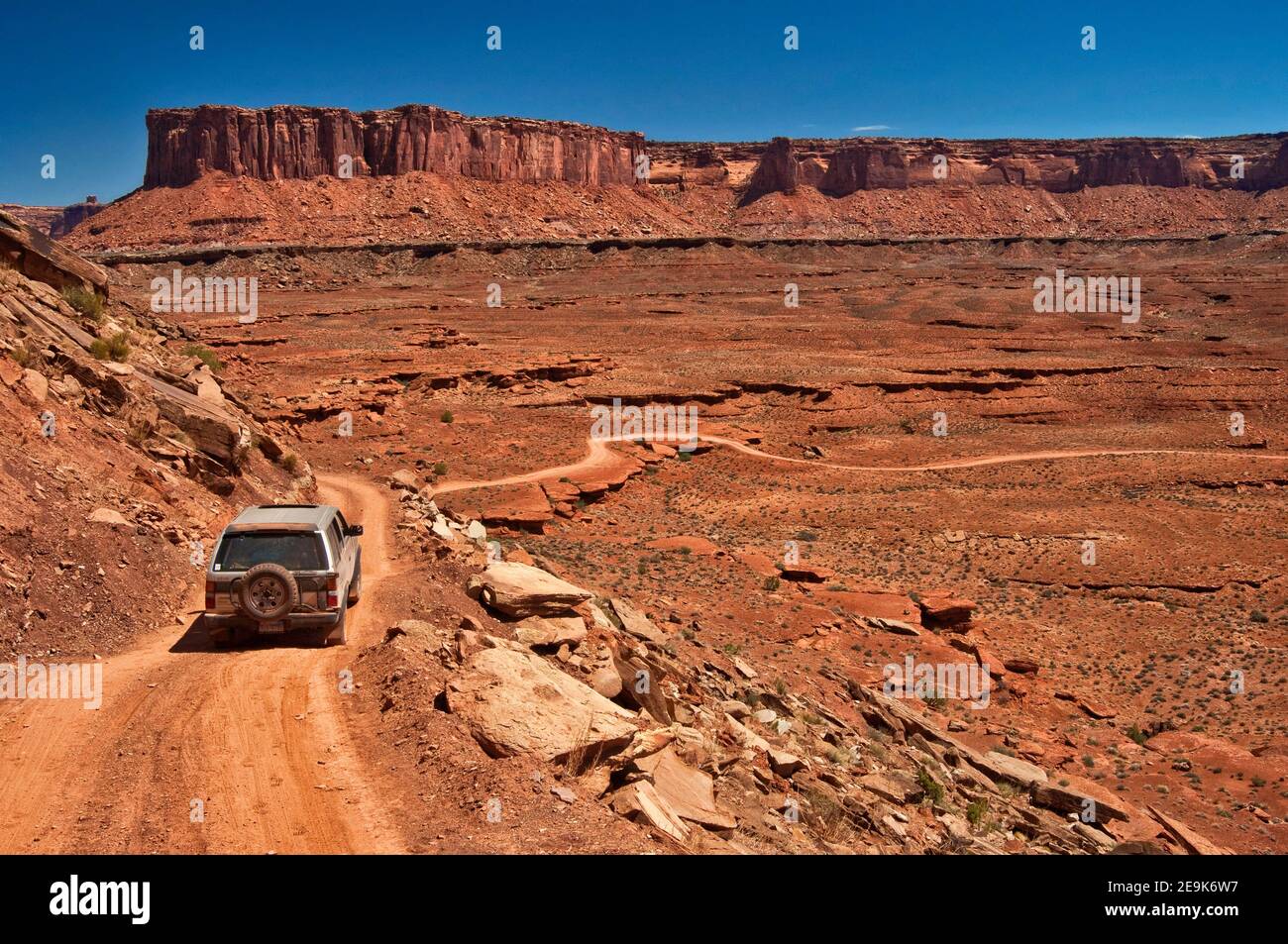 Veicolo 4x4 su White Rim Road, a Murphy Hogback, Murphy Point scogliere in lontananza, Canyonlands National Park, Utah, USA Foto Stock