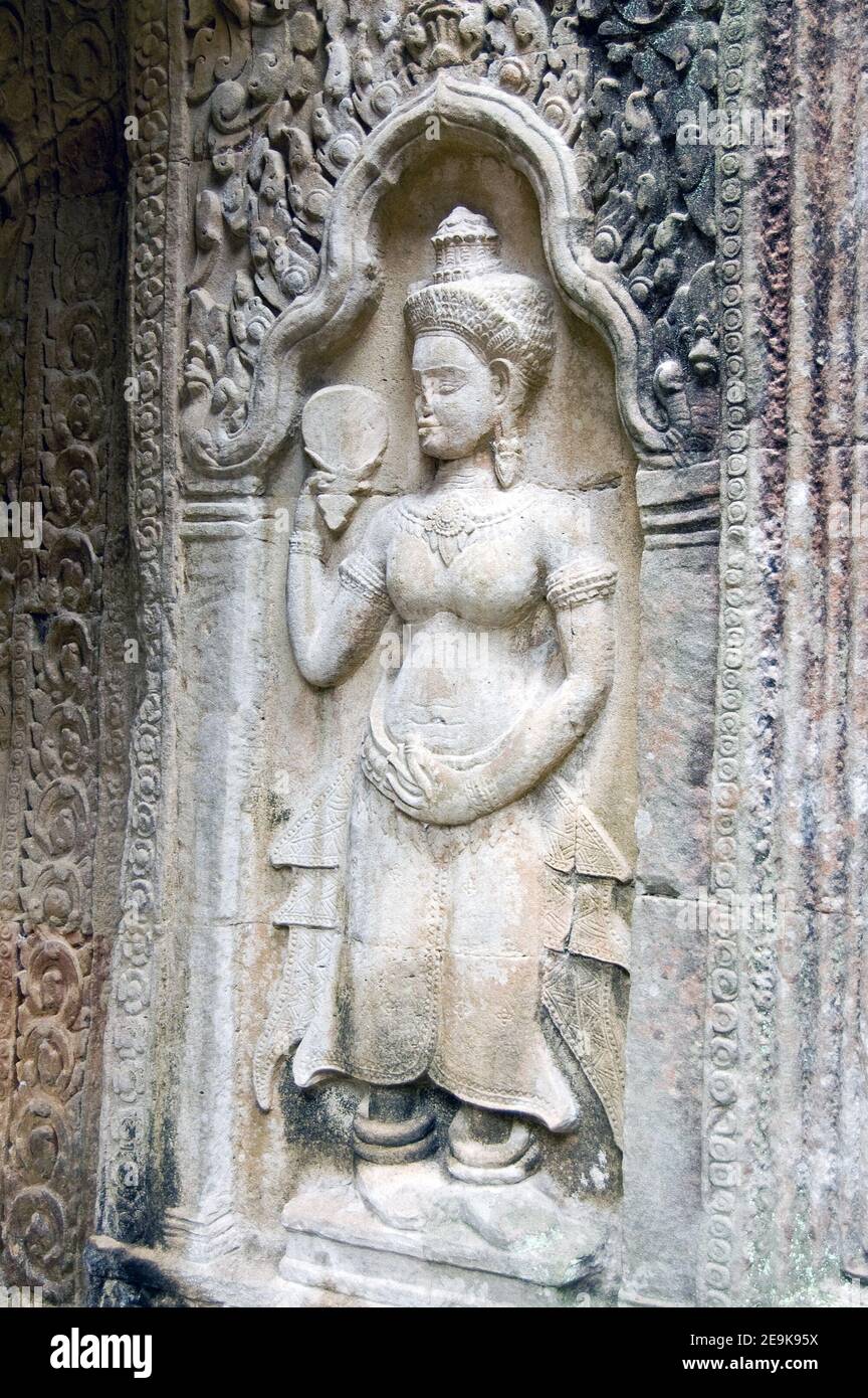 Antica scultura in bassorilievo Khmer di una divinità Apsara che tiene un ventilatore o uno specchio di vetro che guarda. Pilastro interno del tempio di Preah Khan, Angkor, Siem Re Foto Stock