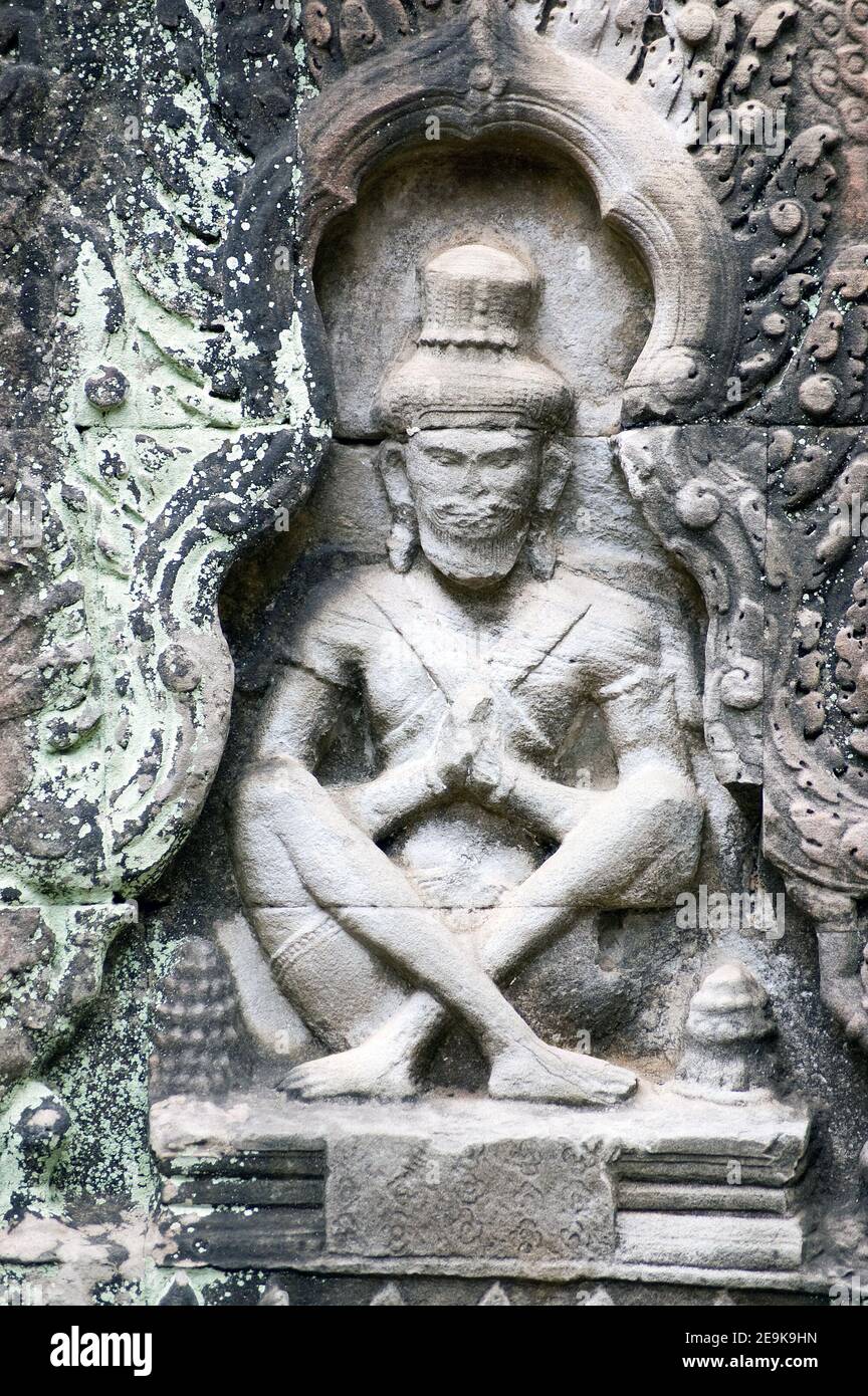 Bas rilievo scultura sulla parete esterna di un 'oratorio' presso l'antico tempio Preah Khan, Angkor, Cambogia. L'ascetico orante è stato scolpito in ancien Foto Stock