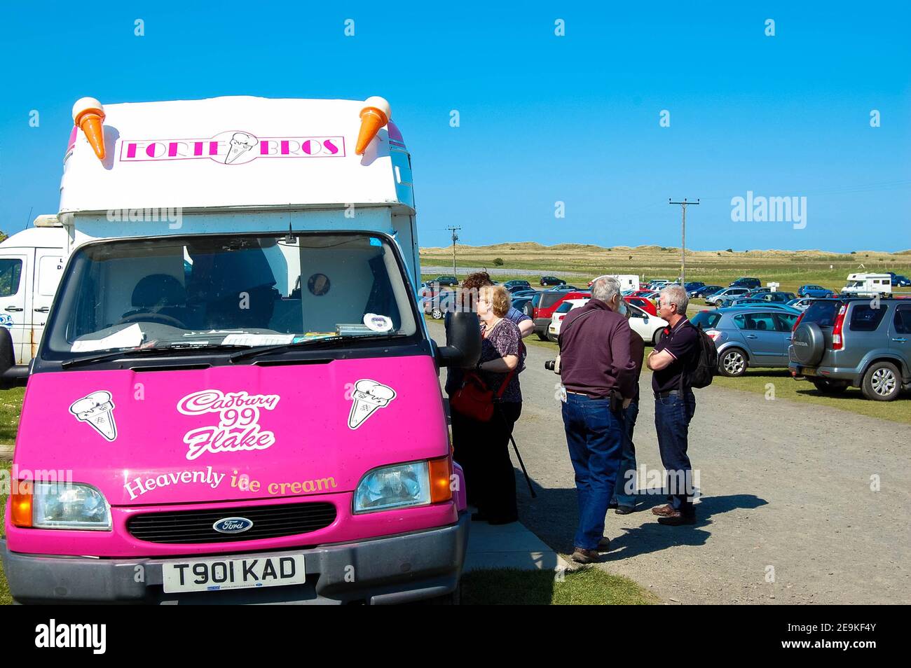 Ice-cream van Northumberland coni cono 99 fiocco clienti acquisto orologio cercando furgone vendita vendere Lindisfarne parcheggio vacanze meteo estate caldo Foto Stock