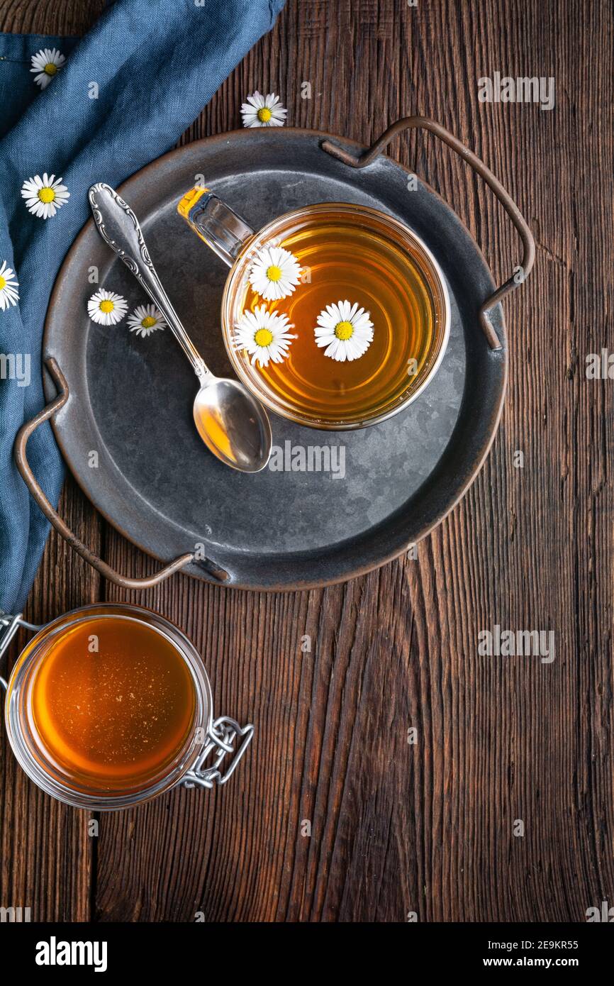 Erboristeria per la salute respiratoria, una tazza di tè margherita con miele su sfondo rustico di legno Foto Stock
