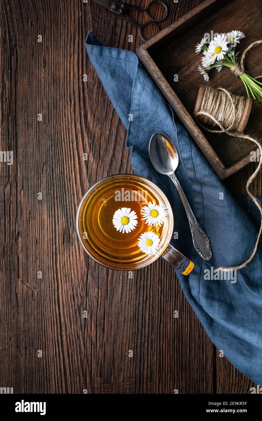 Medicina di erbe per la salute respiratoria, una tazza di tè margherita su sfondo rustico di legno Foto Stock