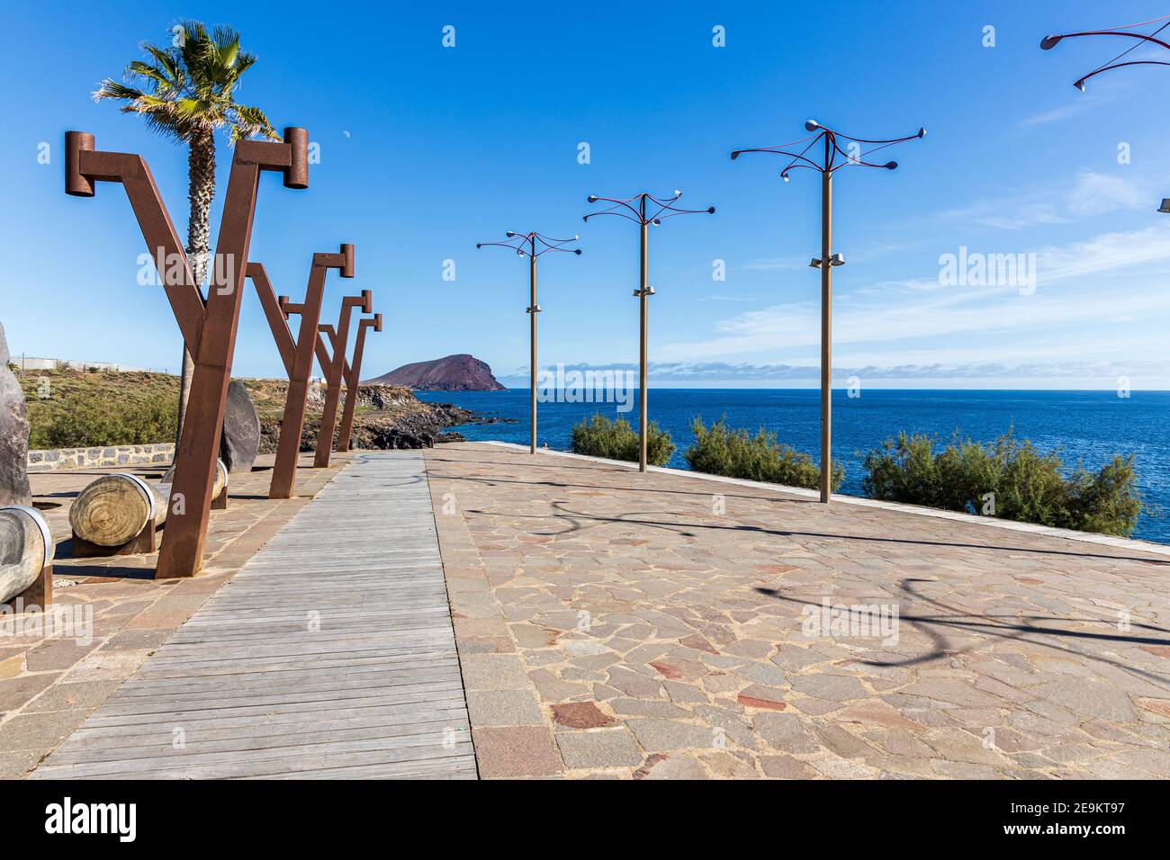 Piccola piazza con sculture del vento su Calle Los Rocas e vista sulla Montana roja, montagna rossa, a Los Abrigos, Tenerife, Isole Canarie, Spagna Foto Stock