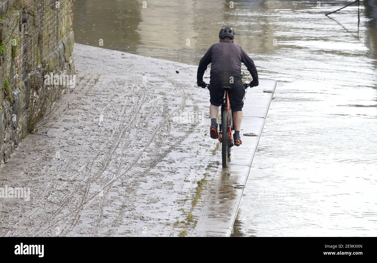 Maidstone, Kent, Regno Unito. Ciclista che costeggia il fiume Medway, su un sentiero coperto di fango dalle recenti inondazioni Foto Stock