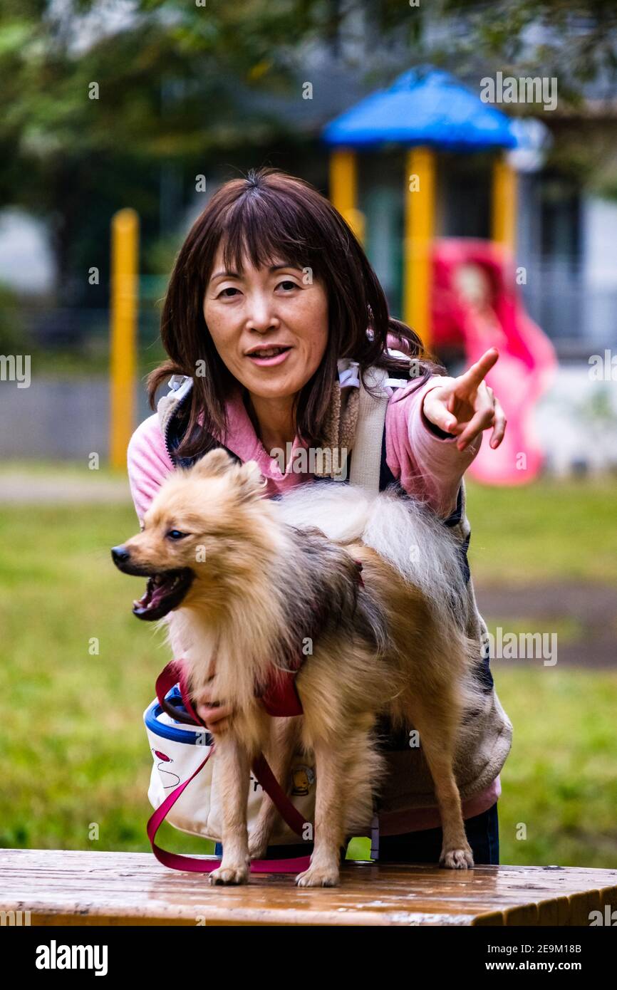 Una donna giapponese e il suo cane nel parco Foto Stock