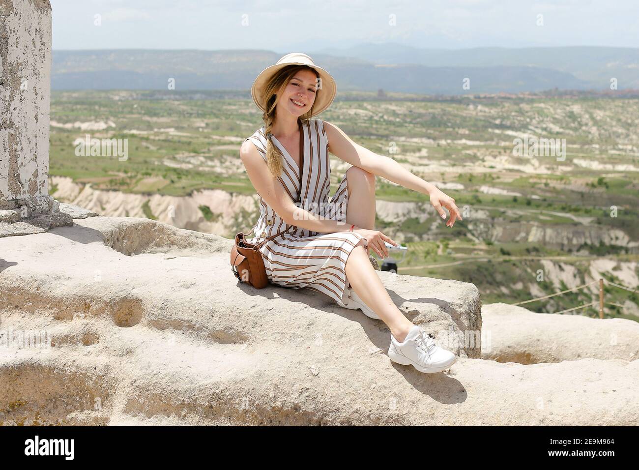Caucasica ragazza seduta sulla roccia, bellissimo paesaggio sullo sfondo, Cappadocia. Foto Stock