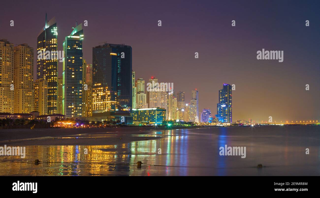 Dubai - La skyline notturno panorama di Marina Towers e mondi più grande ruota panoramica Ferris in costruzione. Foto Stock