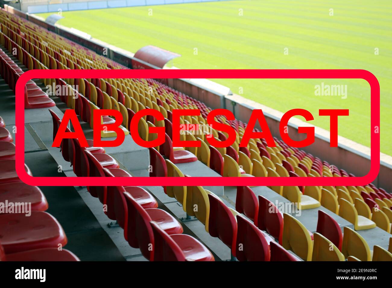 Immagine simbolo: Segno rosso in lettere tedesche con le informazioni (Veranstaltung) abgesagt (evento annullato) con stadio vuoto sullo sfondo Foto Stock