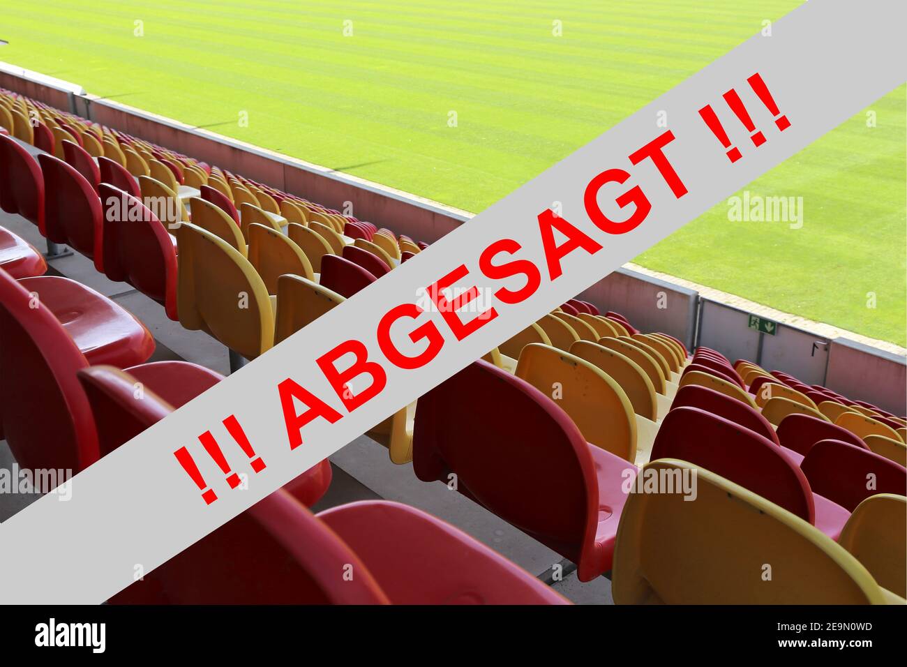 Immagine simbolo: Segno rosso in lettere tedesche con le informazioni (Veranstaltung) abgesagt (evento annullato) con stadio vuoto sullo sfondo Foto Stock