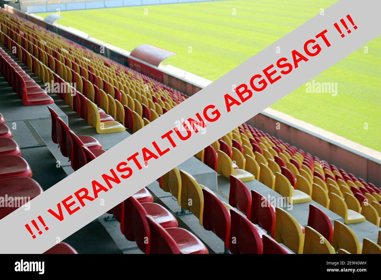 Immagine simbolo: Segno rosso in lettere tedesche con le informazioni (Veranstaltung) abgesagt (evento annullato) con stadio vuoto sullo sfondo Foto Stock