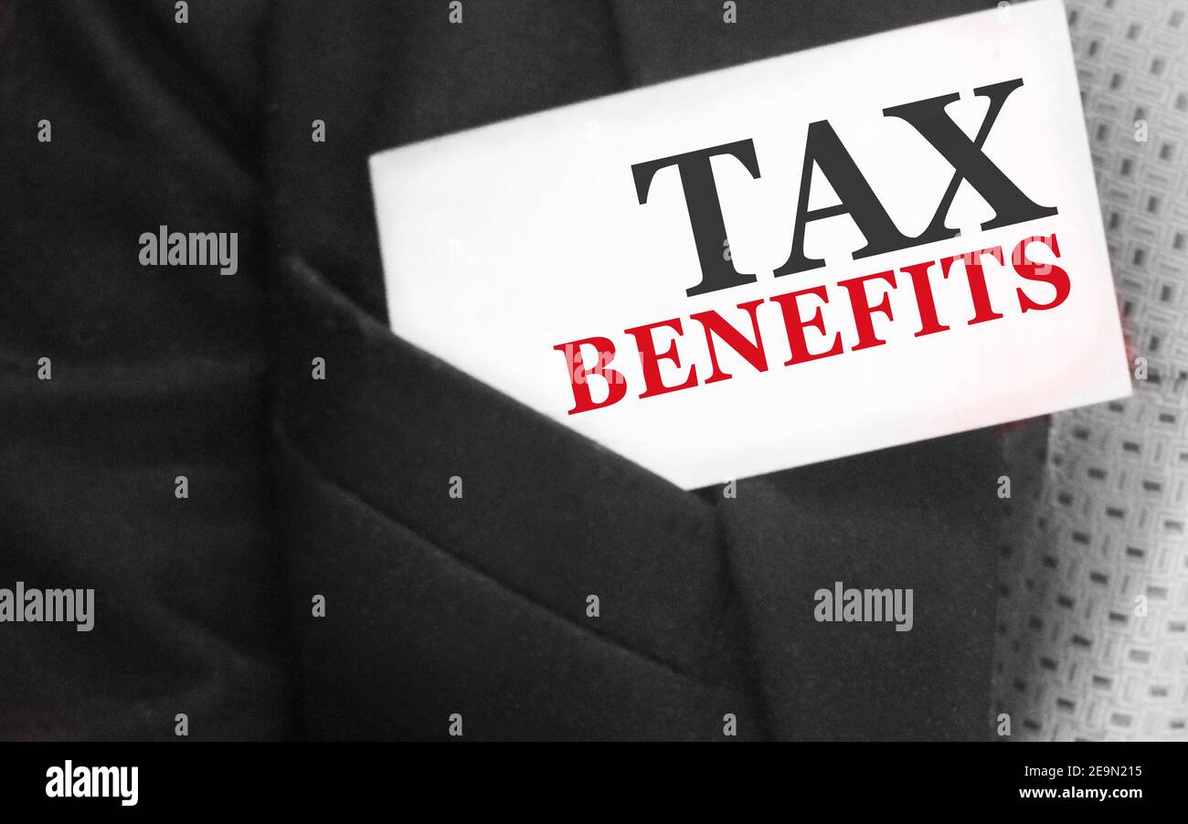 Uomo d'affari mantiene una carta con testo benefici fiscali nella tasca superiore del suo vestito. Concetto di tasse e tasse. Foto Stock