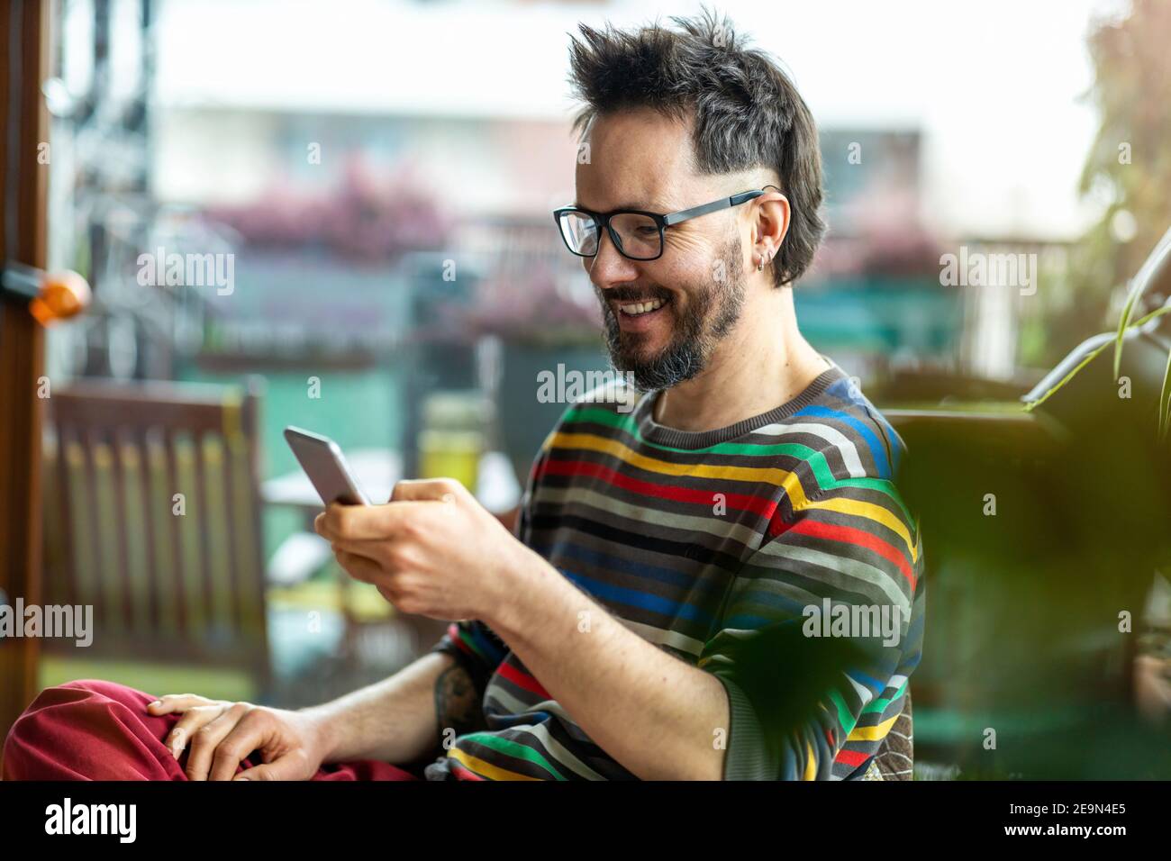 Uomo felice che usa un telefono cellulare a casa Foto Stock