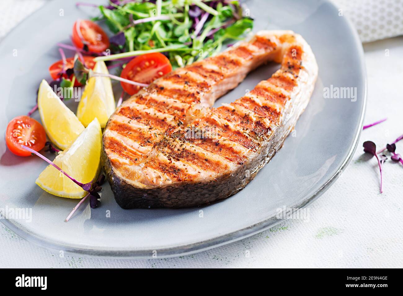 Salmone. Bistecca di pesce al salmone alla griglia e insalata di pomodori con microgreens. Cibo sano. Foto Stock