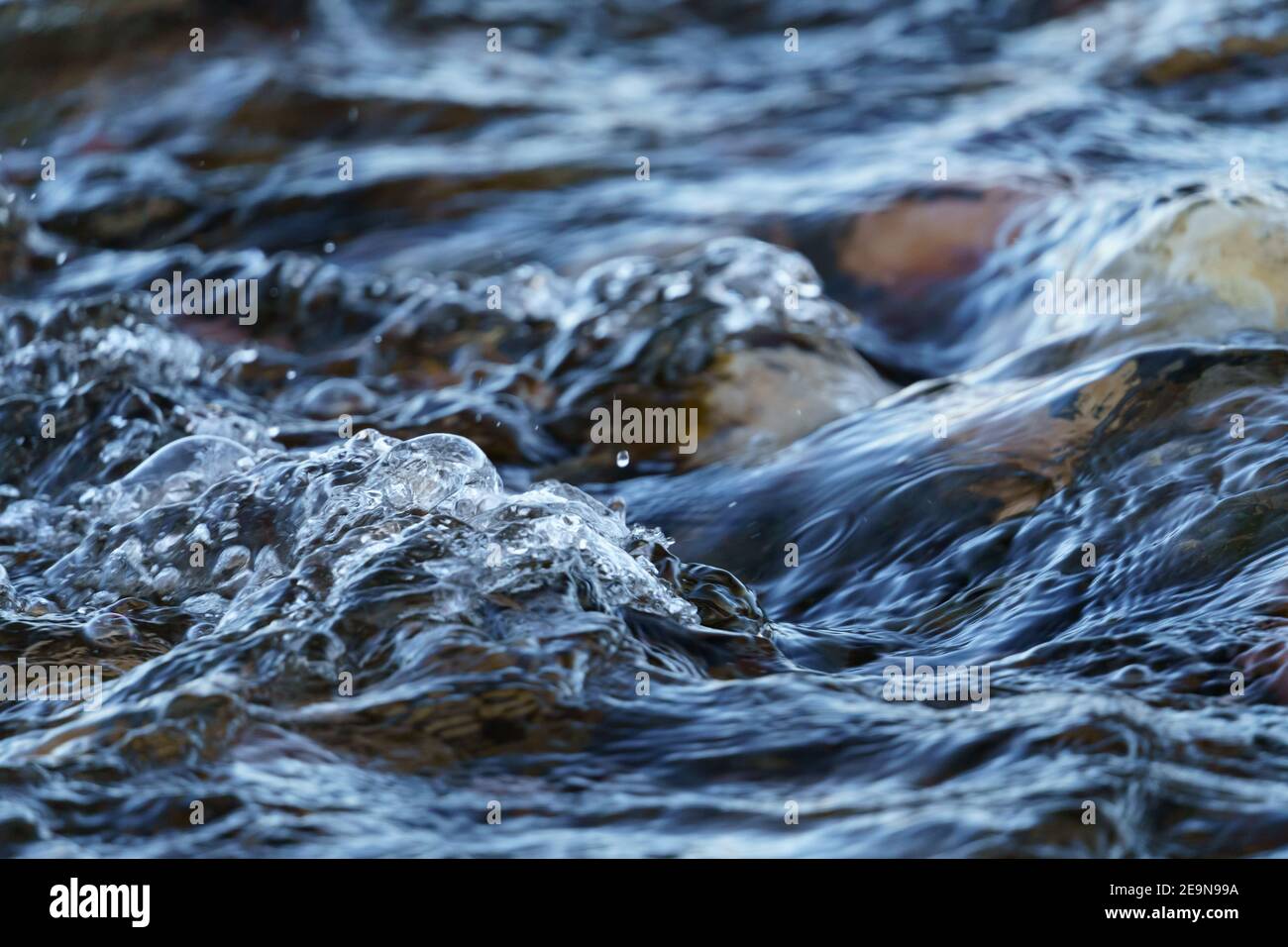 Chiocciatura di acqua di churning sopra Cobblestone in un fiume Foto Stock