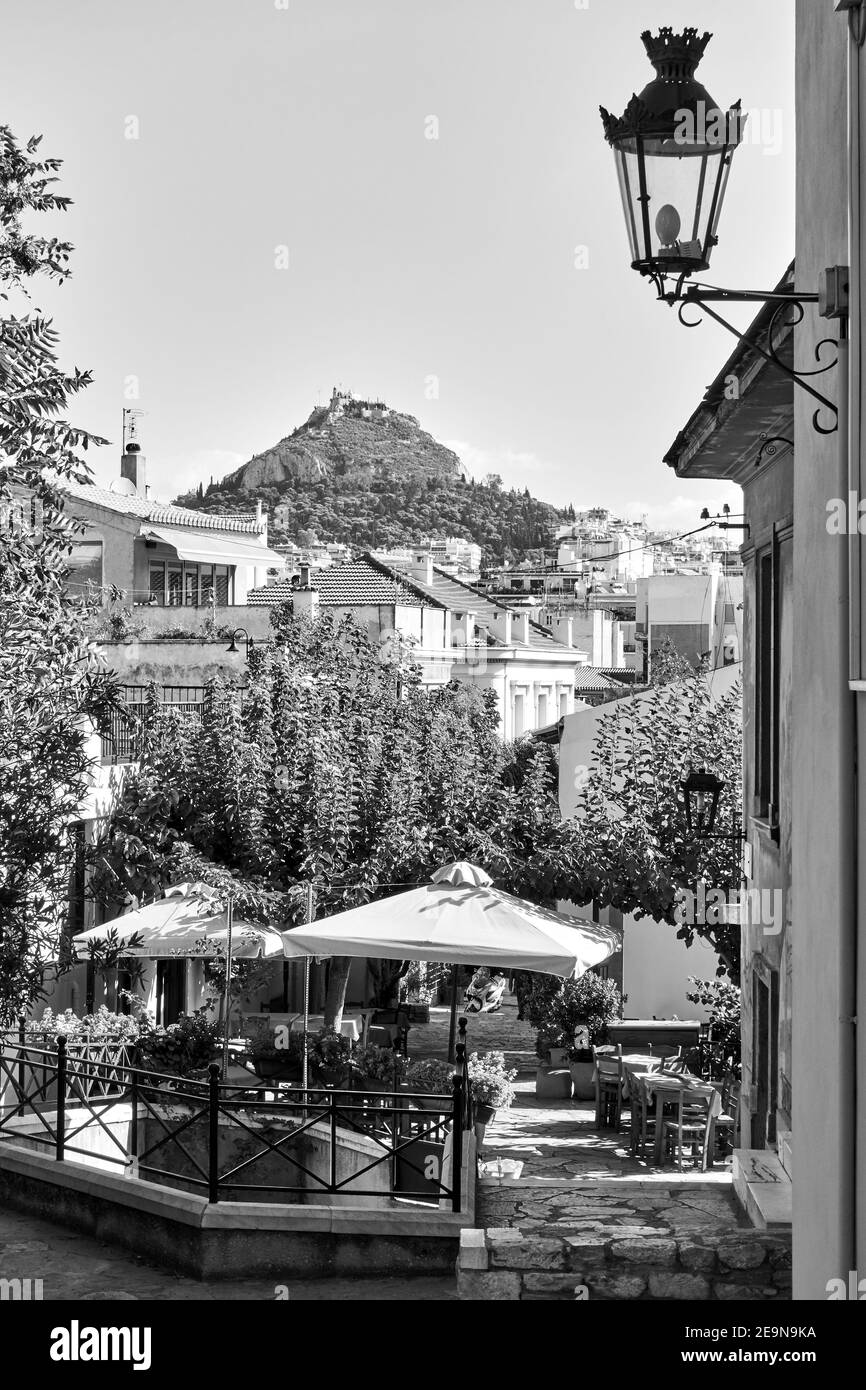 Vecchia strada con caffè all'aperto nel quartiere di Plaka ad Atene, Grecia. Paesaggio urbano greco, fotografia in bianco e nero Foto Stock