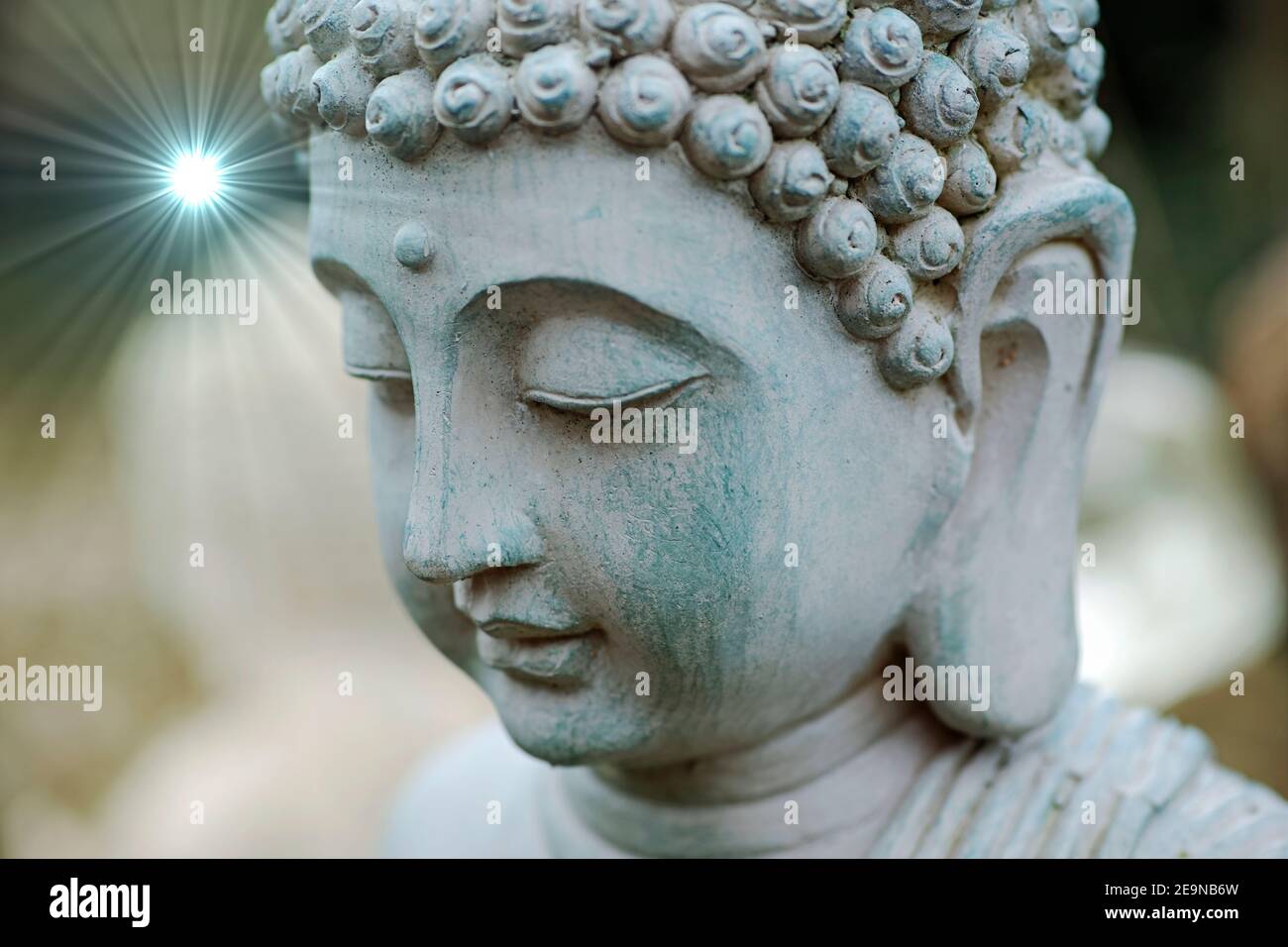 Buddha testa in primo piano. La statua si trova nel nostro giardino. Sullo sfondo è visibile una statua bianca sfocata del buddha Foto Stock