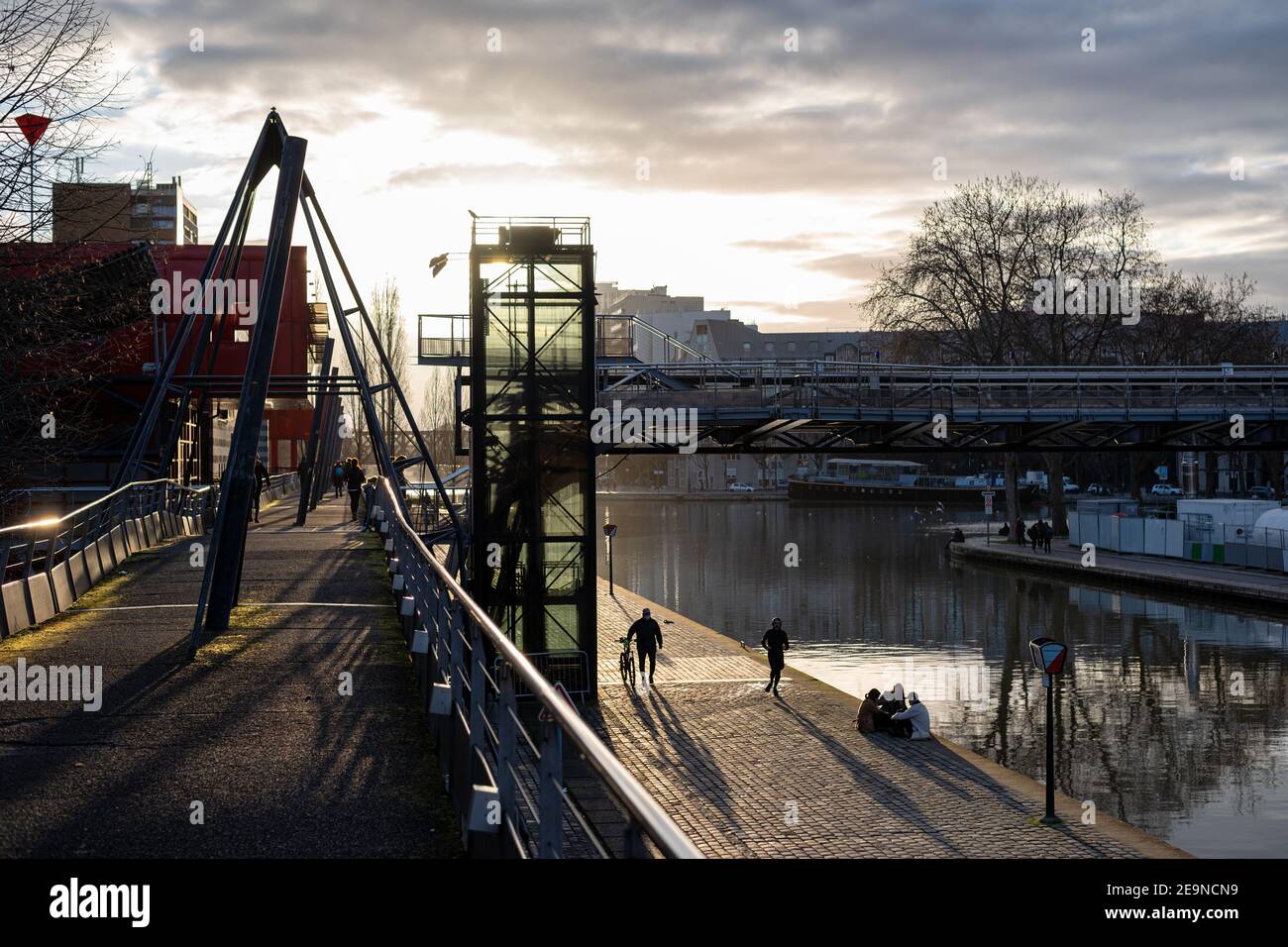 La gente si diverte alla fine della giornata nel Parc de la Villette lungo il Canal de l'Ourcq. Foto Stock