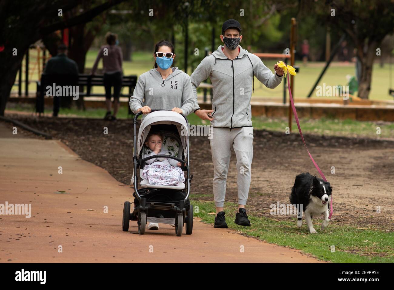 Giovane famiglia che cammina cane mentre indossa maschere il primo giorno dopo il sollevamento di un cinque giorni COVID-correlati 'blocco' a Perth, Australia Occidentale Foto Stock