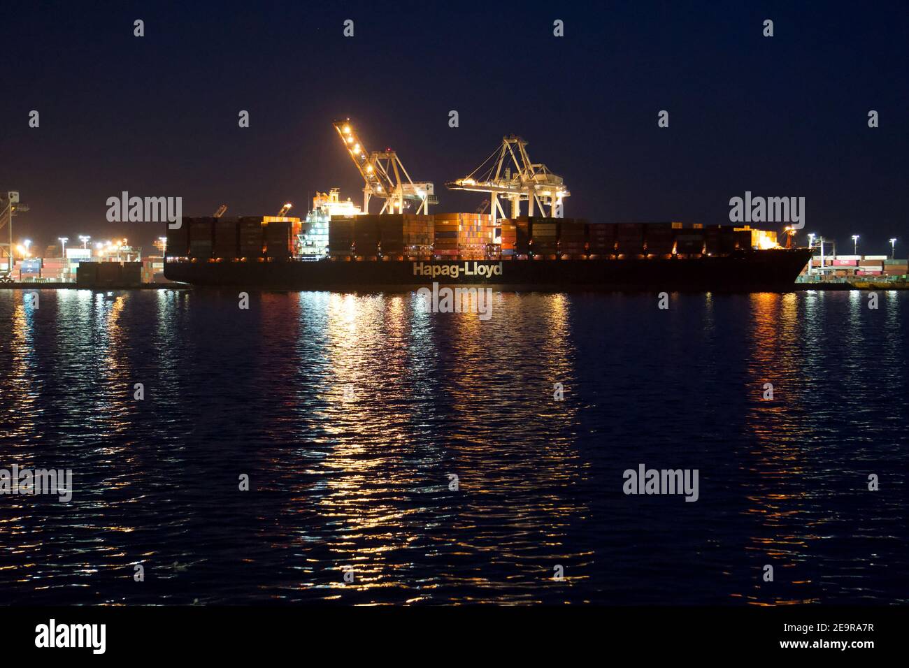 Hapag-Lloyd: Chiatta per container impilata di notte con container per spedizioni intermodali con gru di spedizione. Porto di Oakland, California, USA Foto Stock