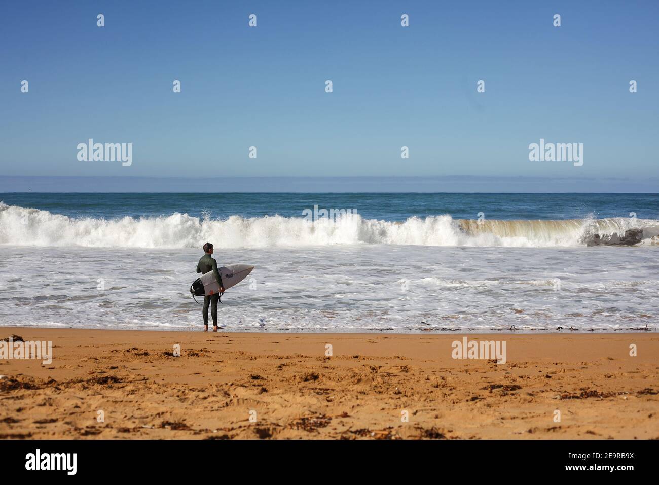 Un surfista guarda le onde dell'Oceano Meridionale a Moyji o Point Ritchie a Warrnambool, Southwest Victoria, Australia Foto Stock