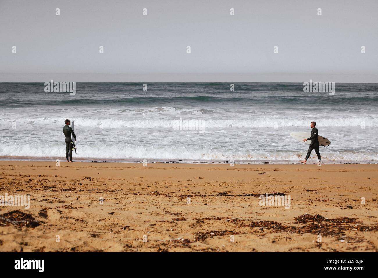 Due surfisti si affacciano sulle onde dell'Oceano Meridionale a Moyji o Point Ritchie a Warrnambool, Southwest Victoria, Australia Foto Stock