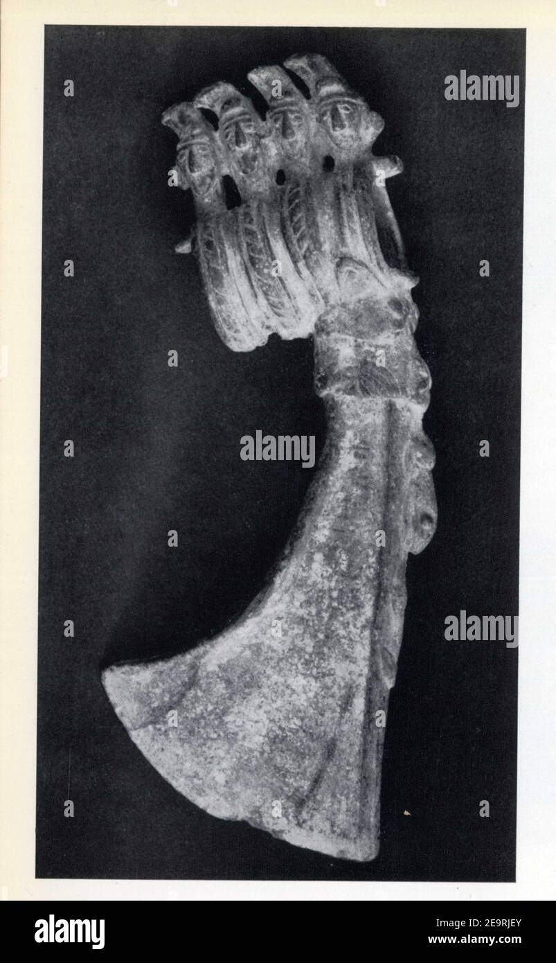 Hache en bronze.Lame crachée par un animal.Talon orné de quatre Têtes humaine coiffées de hauts bonnets pointus du type cimmérien.Iran.Luristan.VIII-V. Foto Stock