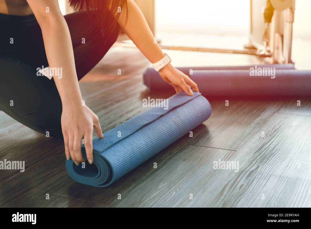 Tappetino yoga, donna in forma sana arrotolando il foglio di gomma di esercizio per la prima classe in club sportivo Foto Stock