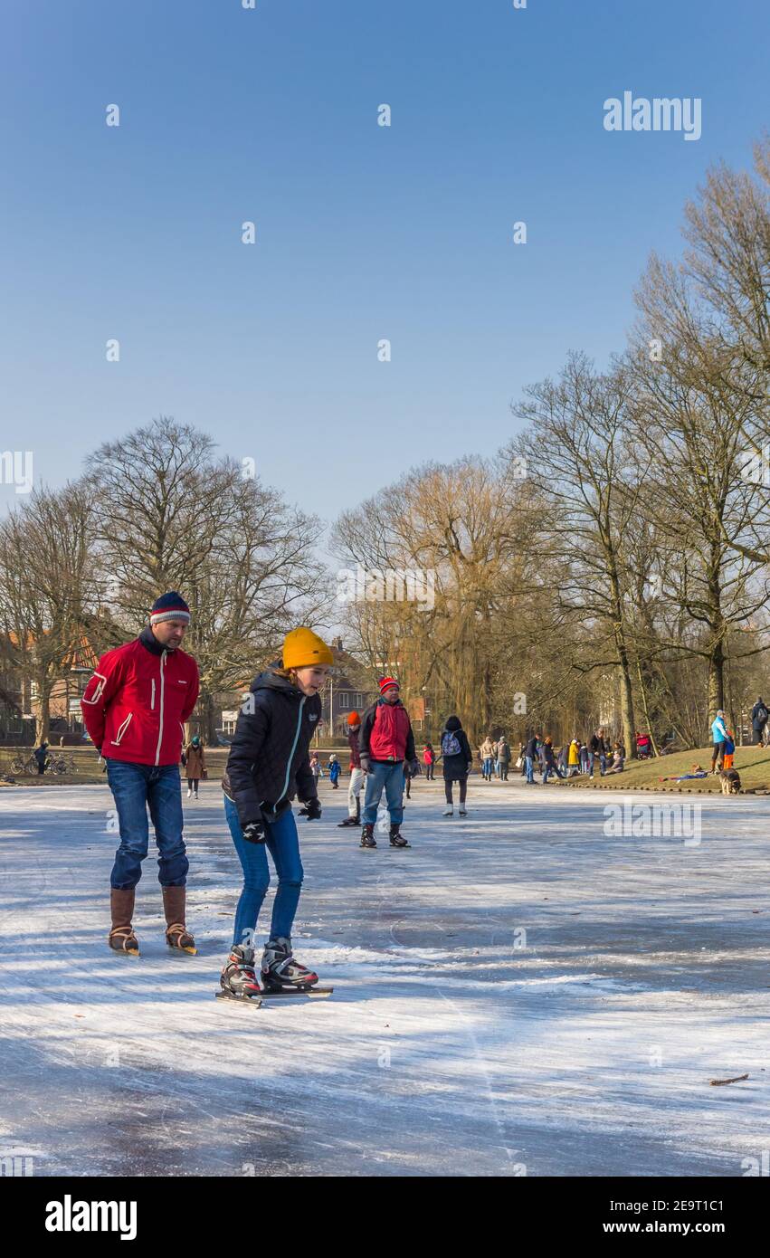 Padre e figlio su pattini sul ghiaccio in un parco a Groningen, Olanda Foto Stock