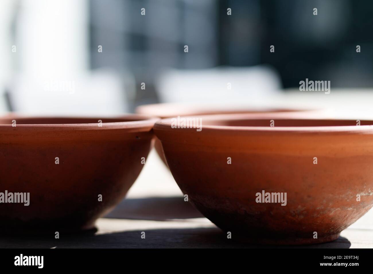 Tre vasi di piante di terracotta su un tavolo, che colano ombre, con fuoco selettivo Foto Stock