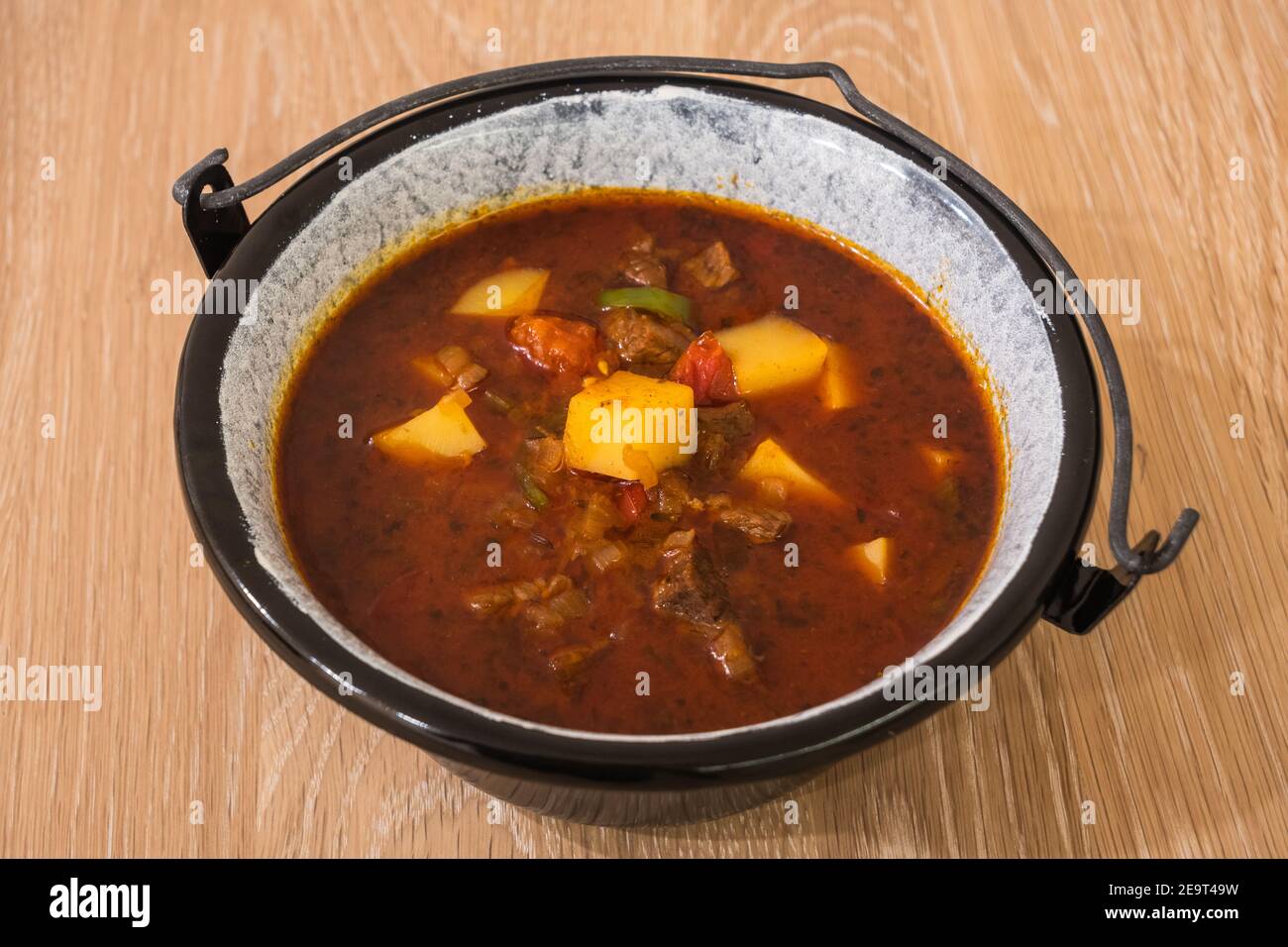 Goulash di manzo ungherese o zuppa di Gulyas o stufato serviti in un piccolo calderone con patate, carne, paprika e pepe Foto Stock