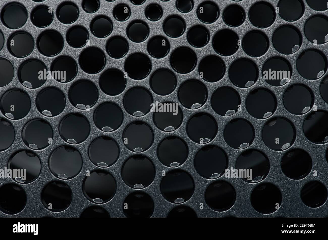 Griglia di fori nella vista ravvicinata macro di superficie nera Foto Stock
