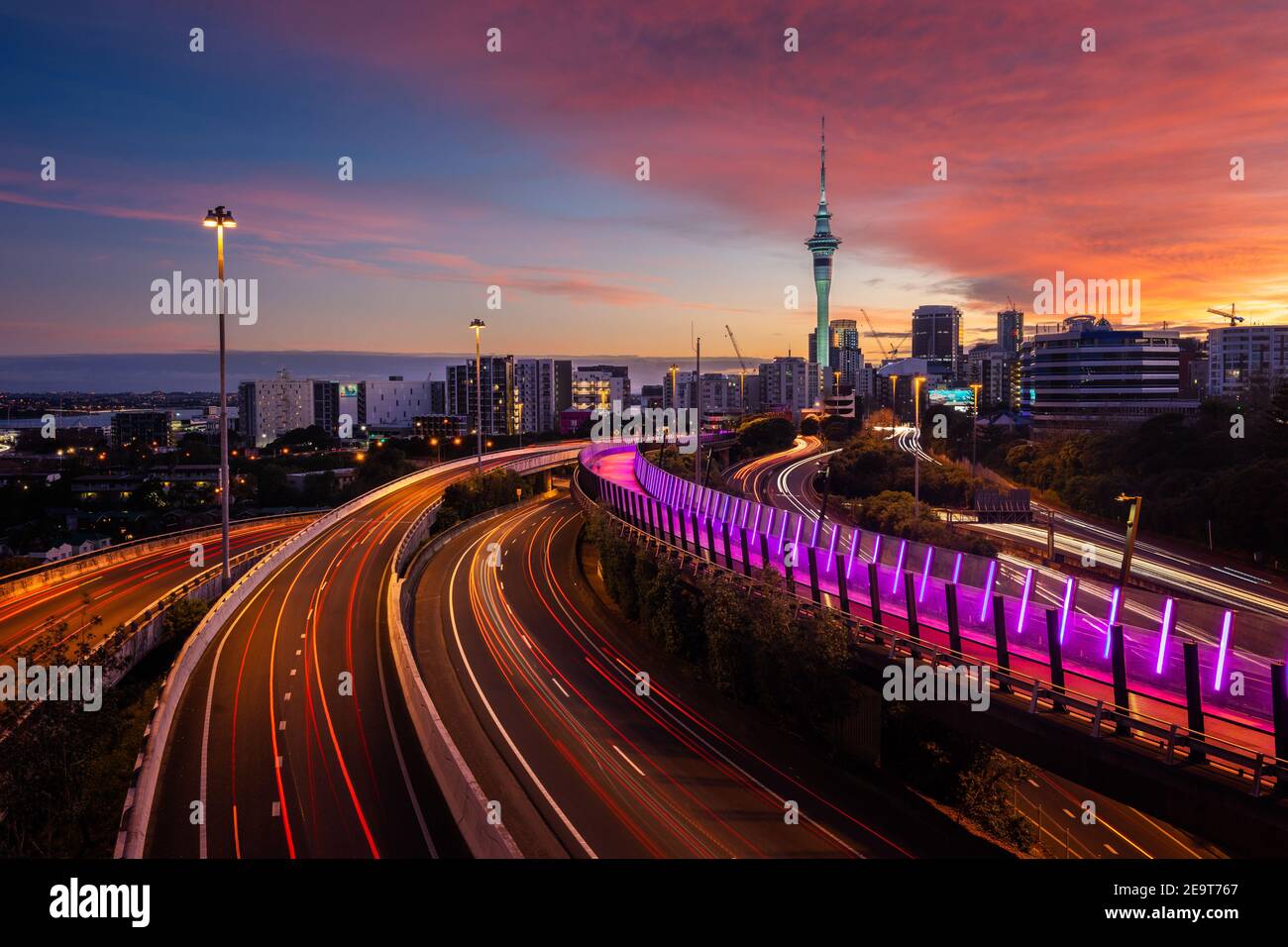 Vista dello skyline di Auckland, della Sky Tower e dell'autostrada con percorsi in auto all'alba. Foto Stock