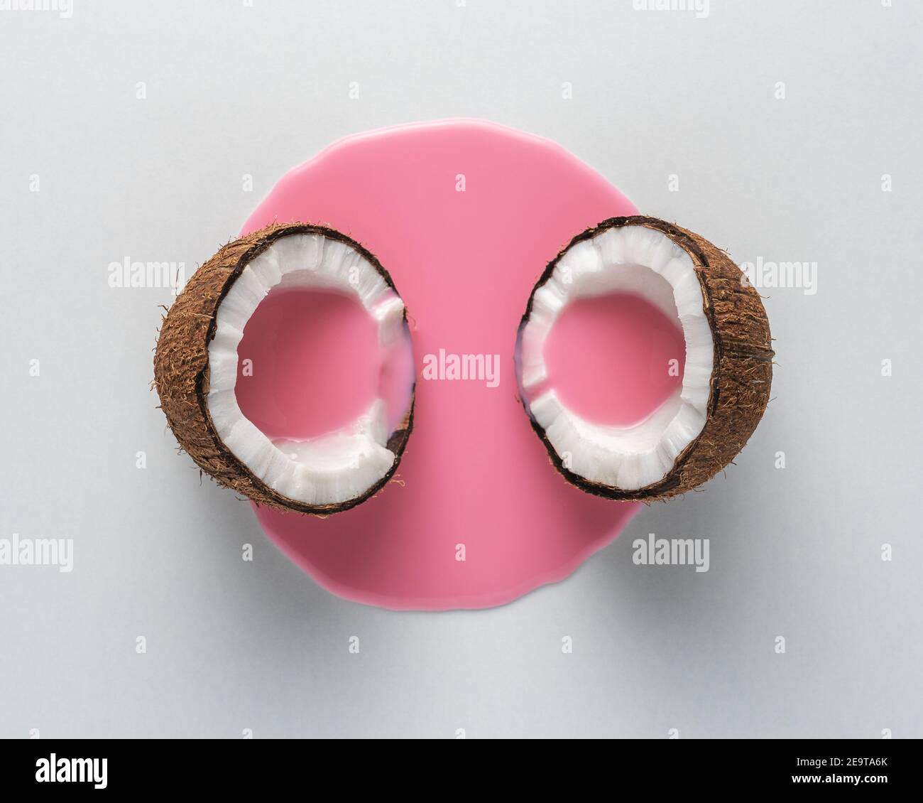 Layout creativo fatto di cocco a metà con versamento di latte rosa. Concetto di cibo minimo. Foto Stock