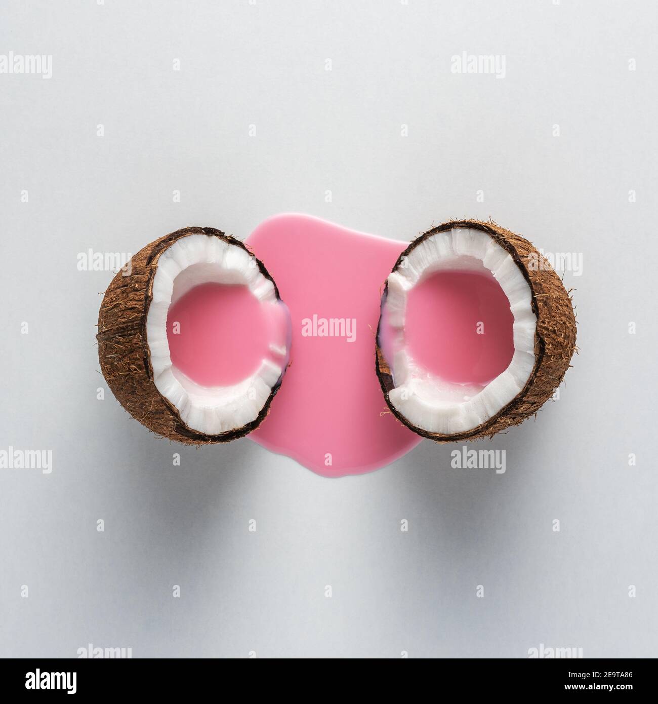 Layout creativo fatto di cocco a metà con versamento di latte rosa. Concetto di cibo minimo. Foto Stock
