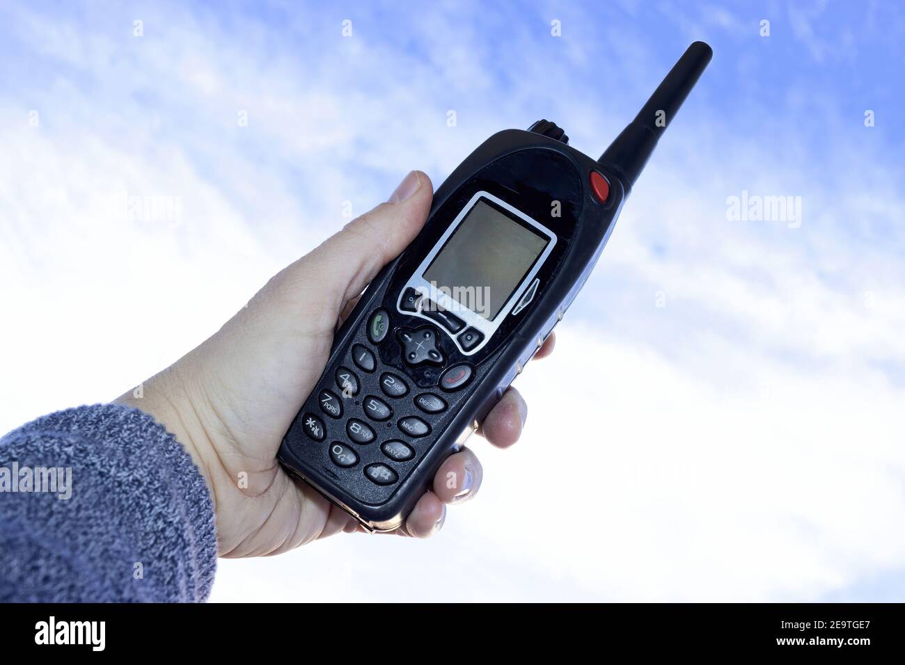 Utilizzando un walkie talkie, apparecchiature di telecomunicazione contro il cielo blu Foto Stock