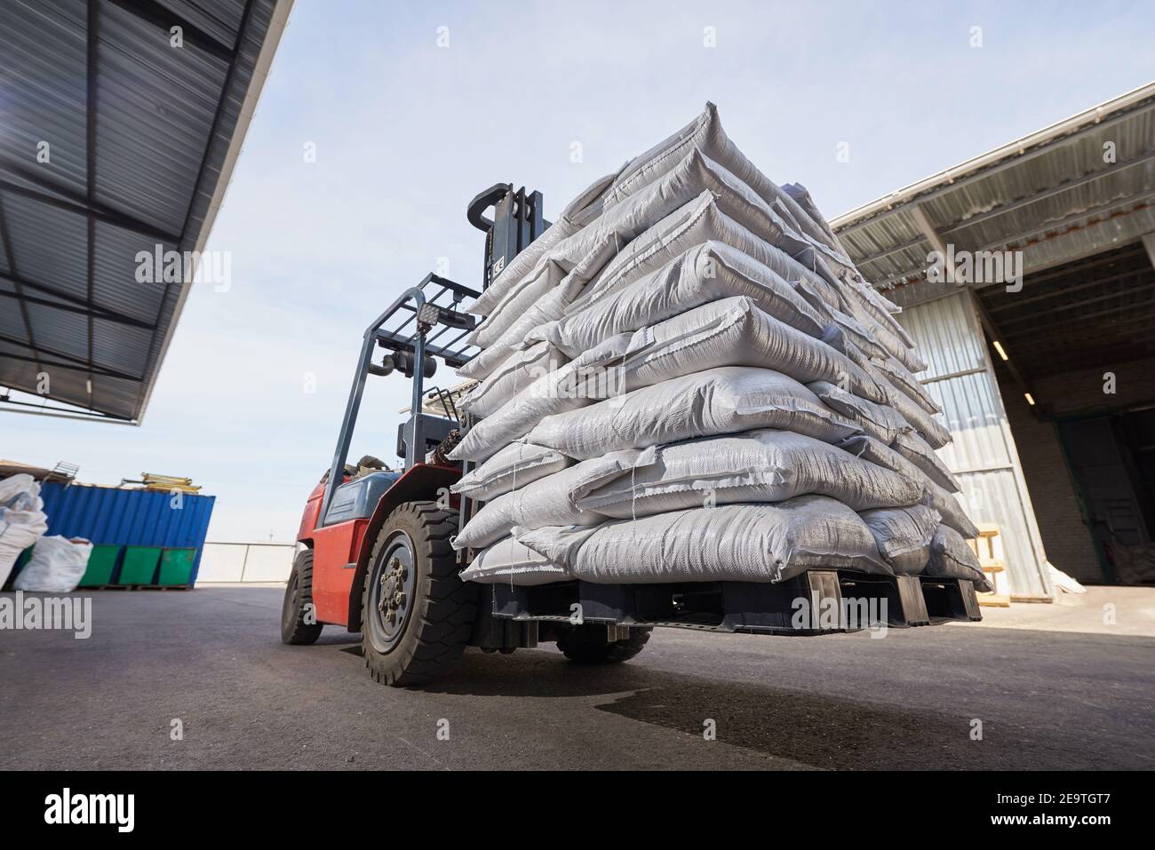 Il carrello elevatore a forche rosso solleva pallet con sacchi pesanti Foto Stock