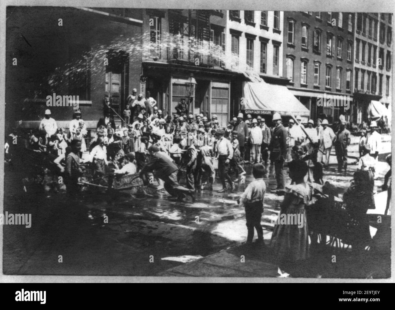 Bambini N.Y.C. in tempo caldo, giocando in spray di idrante di fuoco, poliziotti in attesa Foto Stock