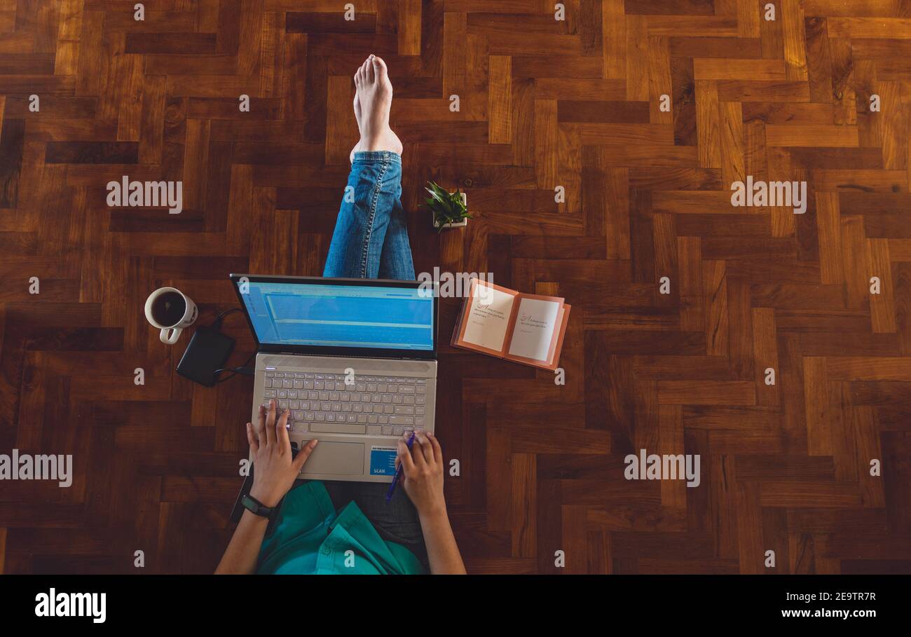 Donna PROFESSIONISTA IT che lavora da casa con notebook e telefoni con una tazza calda di caffè accanto e un verde pianta Foto Stock