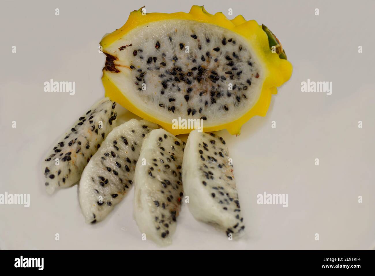 Un drago con pelle gialla, o pitaya giallo, Hylocereus megalanthus, con polpa bianca, tagliato a metà lunghezza e tagliato a fette Foto Stock