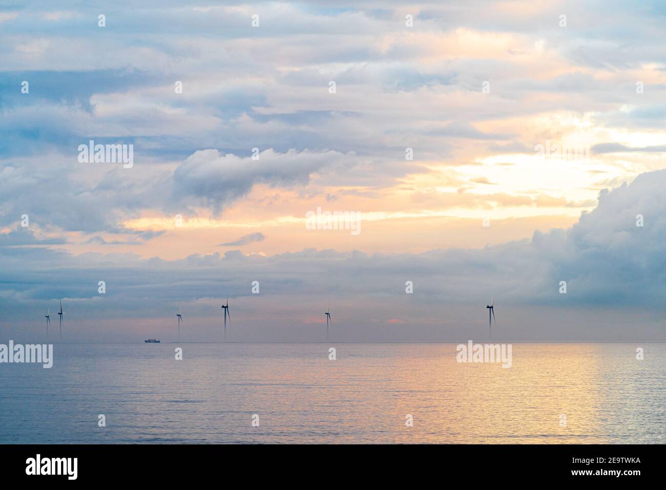 Turbine eoliche del London Array offshore proveniente dall'alba della nebbia mattutina al largo della costa del Kent a Herne Bay. Le cime delle turbine sono visibili con un cielo nuvoloso e grigio con striature arancioni. Il mare è calmo con la nebbia in uno strato sopra di esso. Foto Stock