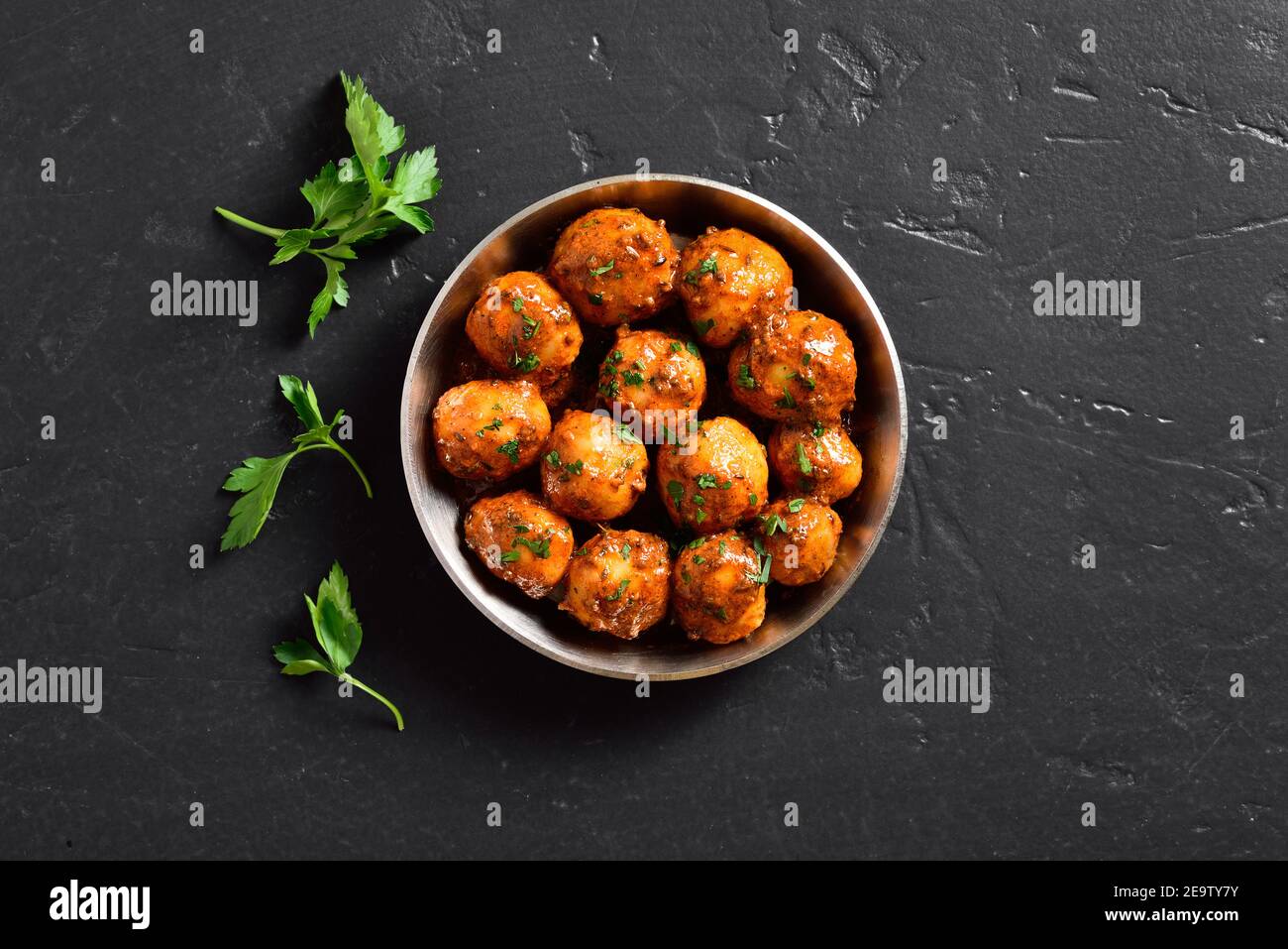 Patate Bombay. Pan patate fritte piccolo bambino con i semi di jeera e coriandolo in ciotola su sfondo scuro con spazio libero di testo. Popolare piatto indiano. Foto Stock