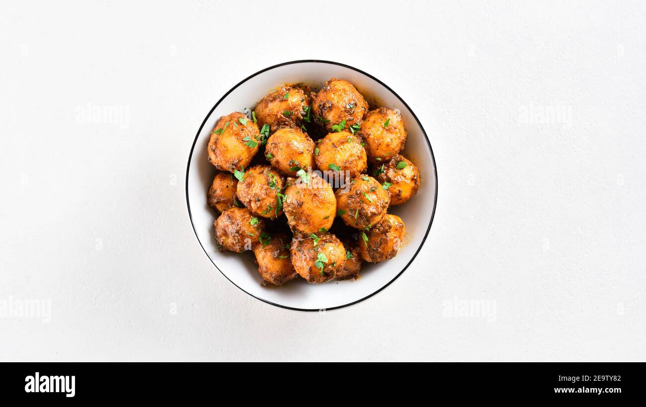 Patate Bombay. Pan patate fritte piccolo bambino con i semi di jeera e coriandolo in ciotola su sfondo chiaro con spazio libero di testo. Popolare piatto indiano. Foto Stock