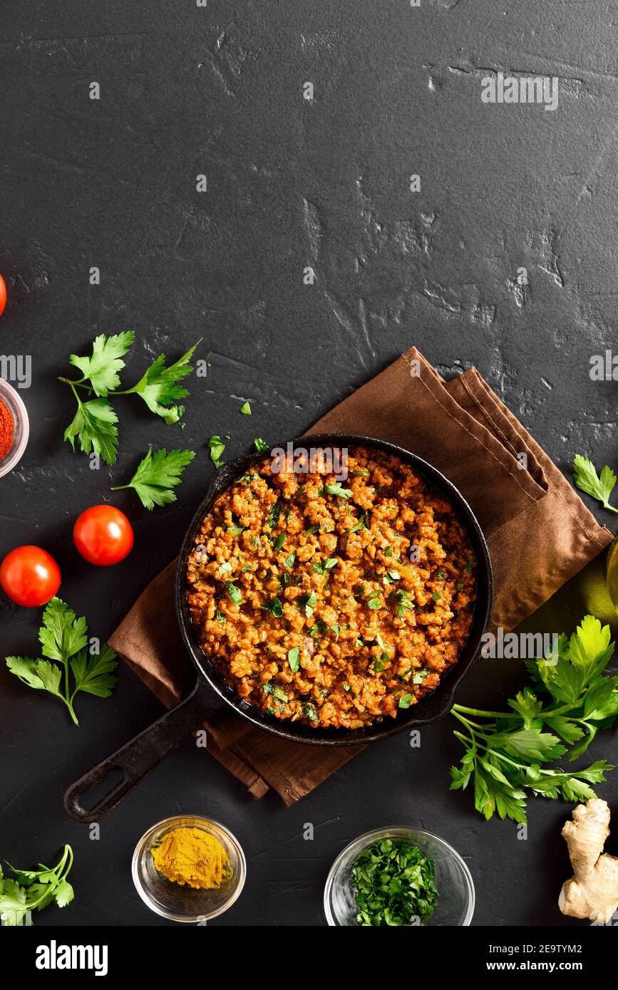 Keema curry in padella su sfondo di pietra nera con spazio di copia. Piatto indiano e pakistano. Vista dall'alto, disposizione piatta Foto Stock