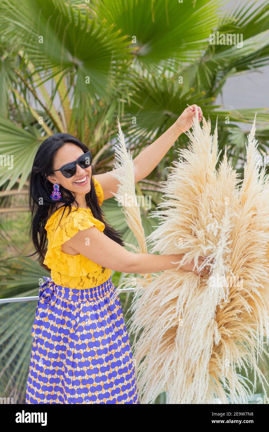 Carino donna latina ama organizzare la sua pampas erba fiore arrangiamento Foto Stock